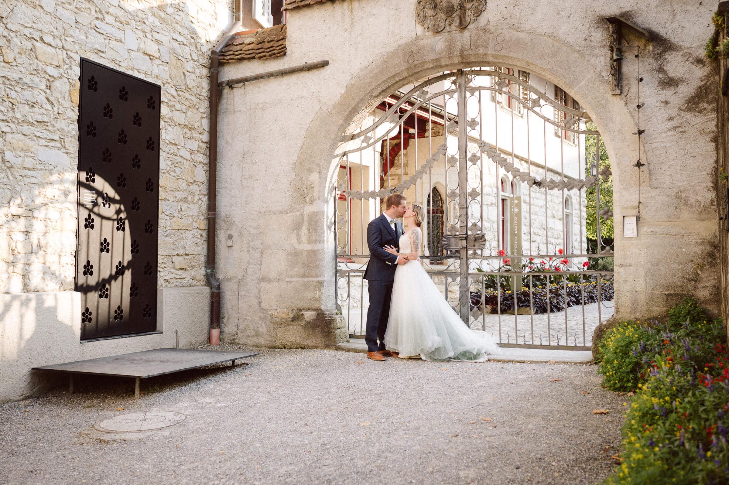 Bride and groom standing beneath historic stone archway — cinematic wedding portrait by David Rickenbach, destination photographer in Europe.