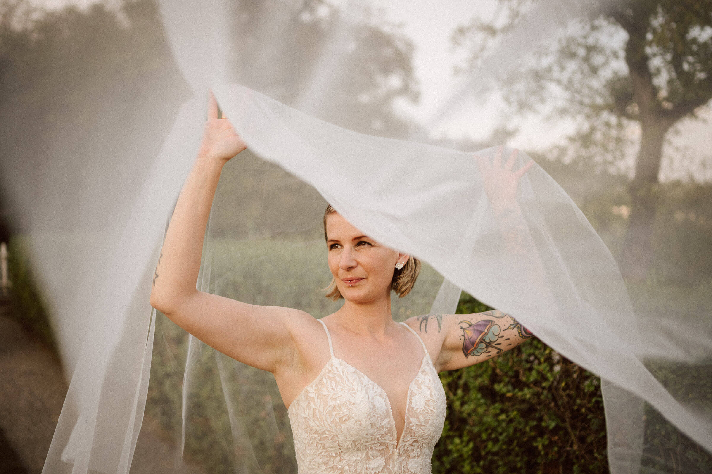 Bride lifting her veil in soft evening light, editorial fine art wedding portrait by David Rickenbach.