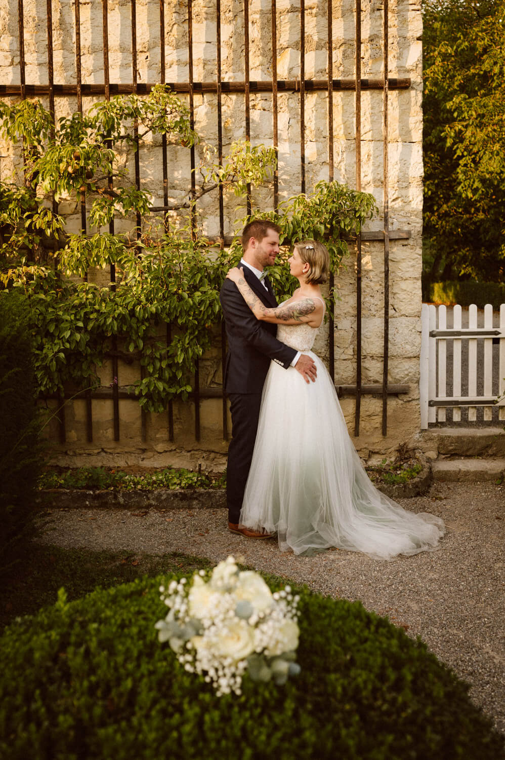 Bride and groom embracing in a garden during golden hour, luxury wedding photography.