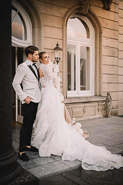 Swiss luxury wedding — exterior portrait at golden hour with the bride’s long lace train; digital.