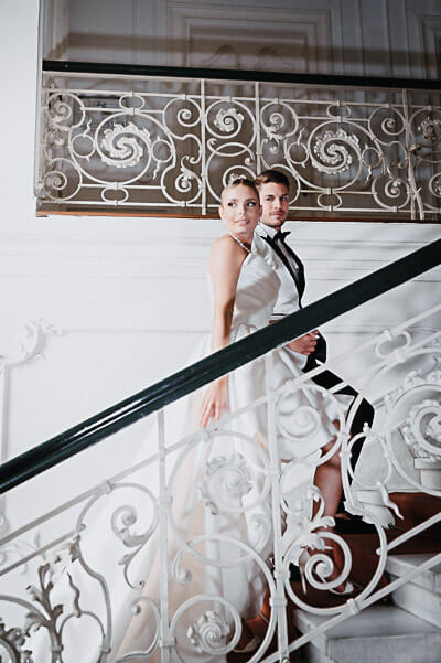 Swiss luxury wedding — couple on an ornate staircase in a grand villa; digital.