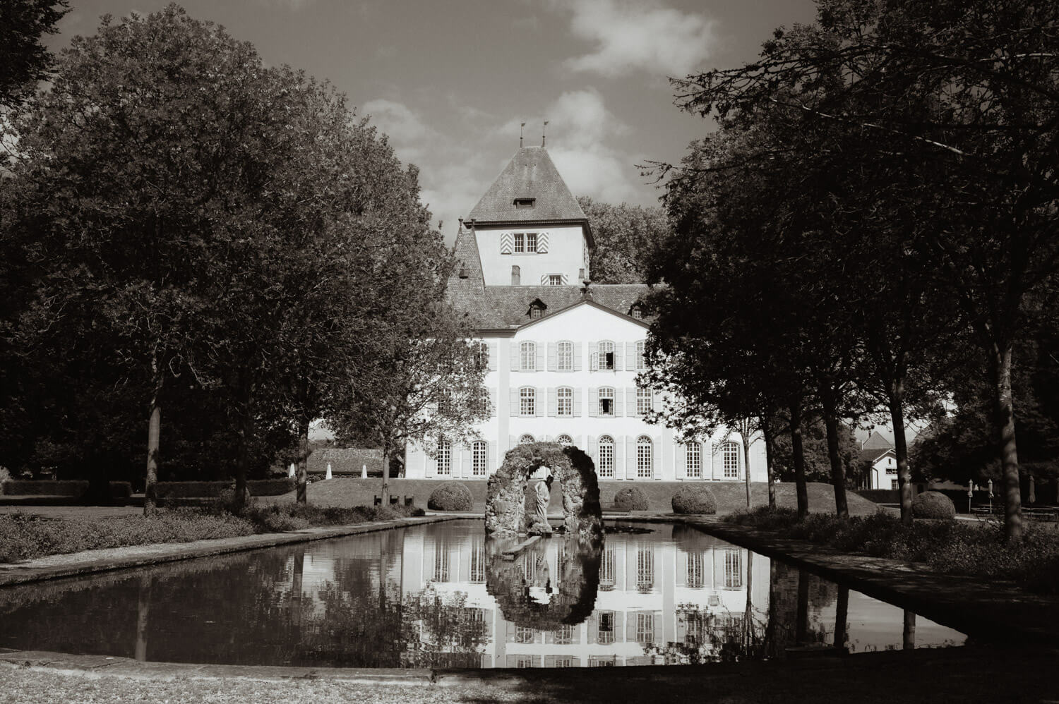 Reflection of a historic Swiss castle in a garden pond during an elegant wedding setting
