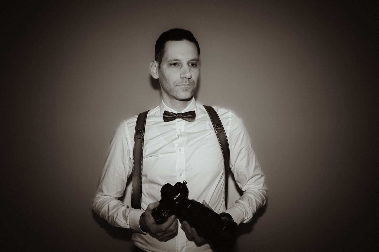 Editorial portrait of wedding photographer David Rickenbach holding a camera with calm, composed presence.